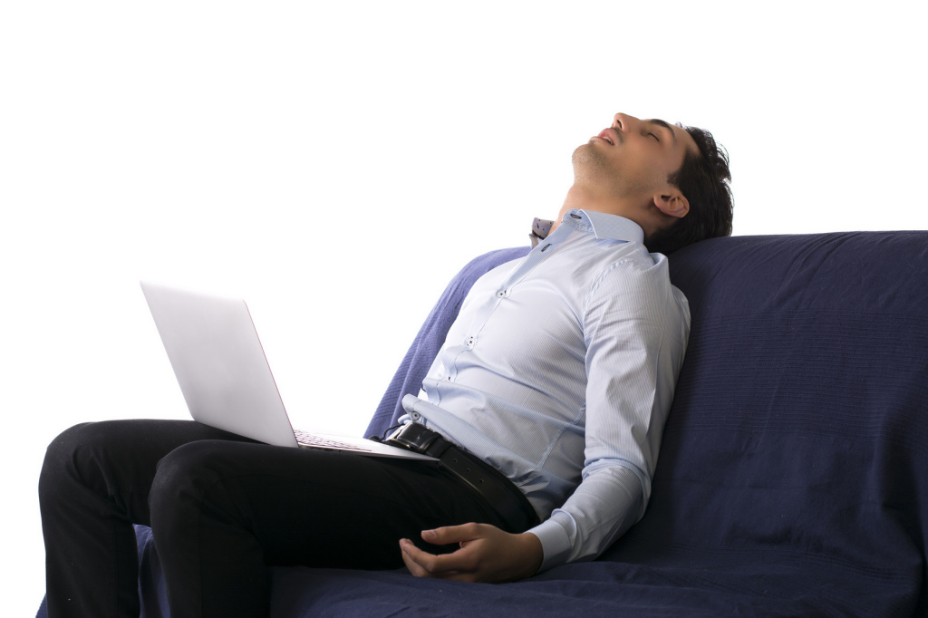 Young man fell asleep on couch white working on laptop computer