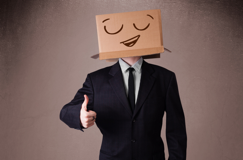 Businessman gesturing with a cardboard box on his head with smil