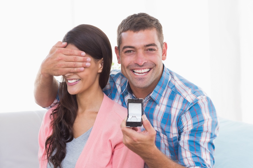 Happy man covering womans eyes while gifting ring
